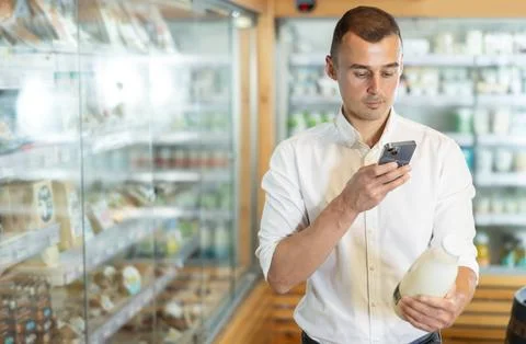 Man in supermarket scan QR code on bottle of milk Stock Photos