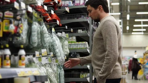 Man in a supermarket selects the line filter of the six cells for the computer. Stock Footage 73430383
