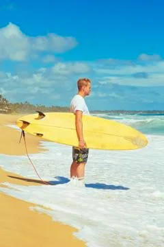 Man with surfboard on the beach at sunset. Stock Photos