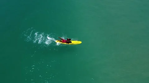 A man on a surfboard rows and stands on a board on a wave Stock Footage 171337281