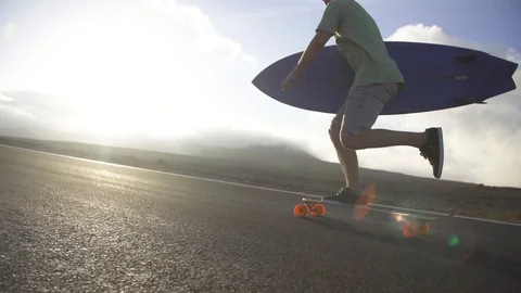 Man with surfboard skating on road Stock Footage 85816894