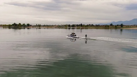 Man surfing hovering over the water behind a boat, aerial drone chasing wake hyd Stock Footage 102689232