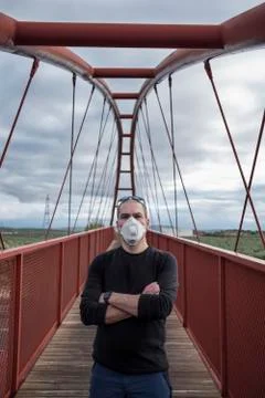 Man with surgery mask looking at camera in pedestrian bridge Stock-Fotos