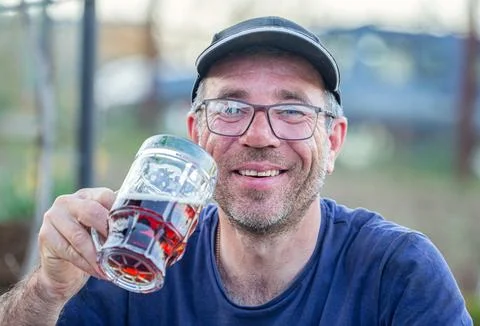 A man is surprised while taking a large glass of beer to his mouth and is very Stock Photos
