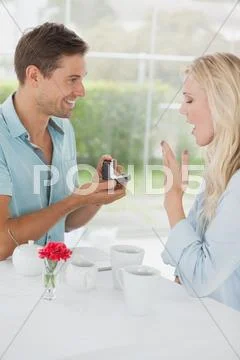 Man surprising his girlfriend with a proposal in cafe Stock Photos