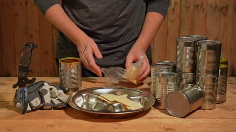 Man survivor preparing meal from old canned food, survival escape in forest.. Stock Footage 325635161