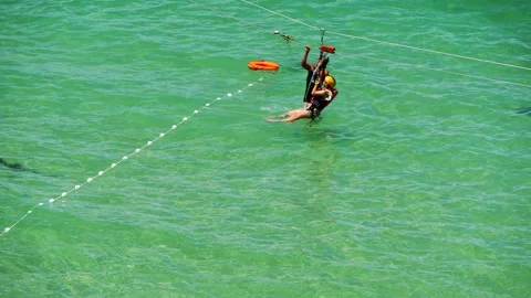 Man suspended by a cable after having fun at zipline and landing in the water Stock Footage 149766278