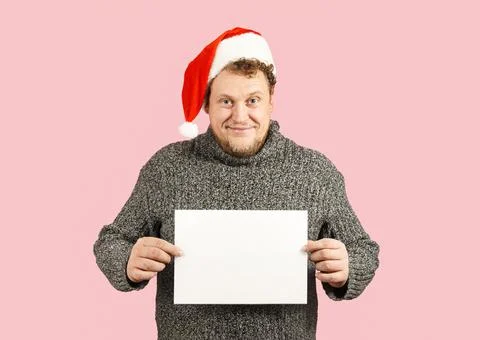 A man in a sweater and a red hat is holding an empty white sheet of paper Stock Photos