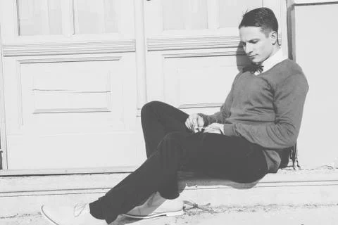 Man in sweater sitting on steps in front of house and posing Stock Photos