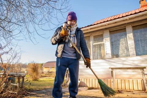 Man sweeping the backyard with a broom. Yard work and outdoor house Фото