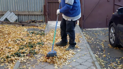 A man is sweeping a path from fallen leaves in his yard. Autumn in the Russian 스톡 동영상 141470253