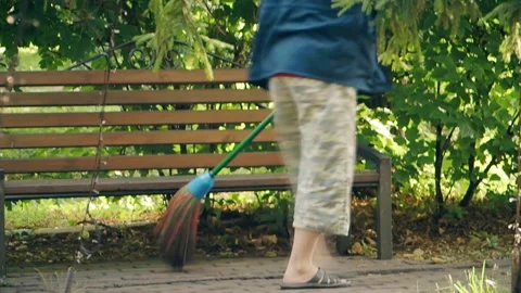 A man sweeps the pedestrian paths in the park during the day Stock Footage 159871855