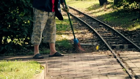 A man sweeps the pedestrian paths in the park during the day Stock Footage 160091921