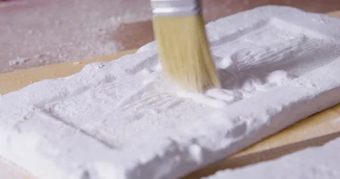 Man sweeps residue from plaster casting mold with pattern Stock Footage 170904060