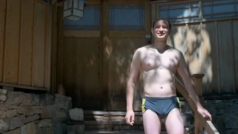 Man in swim trunks walking down steps in outdoor garden in Japan spa onsen Stock Footage 120609364