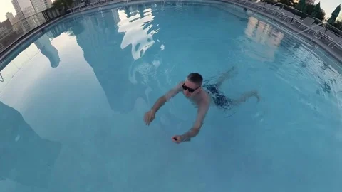 Man Swimming Calmly in Rooftop Pool Surrounded by Beautiful Urban Skyline View Vidéo 291621820