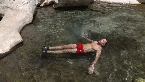 Man swimming, floating in natural pool, super slow motion 240fps Stock Footage