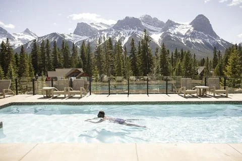 Man swimming in outdoor pool with mountain view Stock Photos