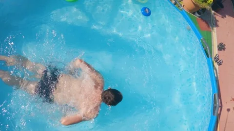 Man swimming in a pool between inflatable children. View from above Stock Footage 241900679
