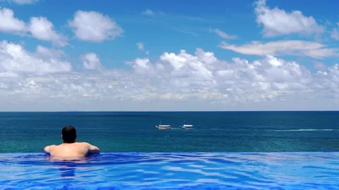 Man in swimming pool with infinite edge enjoying summer 動画素材 149679170