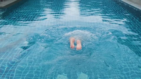 Man swimming in resort pool, surrounded by tropical lush greenery, enjoying Stock Footage 288111652