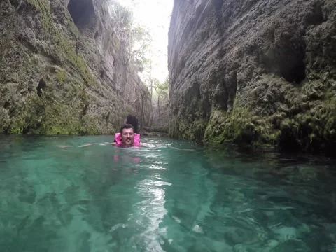Man swimming through cave rivers in Mexico from water level view Stock Footage 147725474
