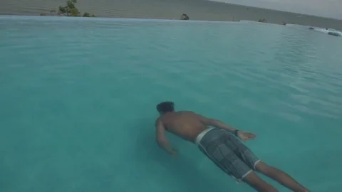 Man Swims in Infinity Pool Overlooking the Ocean Shot in Slow Motion Stock Footage 78760552
