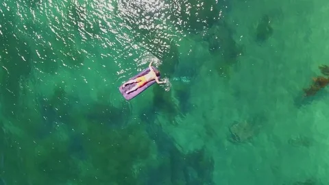 Man swims lay inflatable matrass azure ocean sand beach Triozerye Russia Aerial Stock Footage