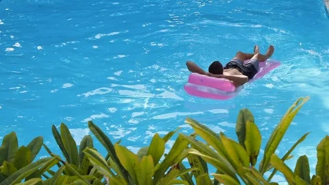 A man swims on a mattress in the pool. Video stock 122768055