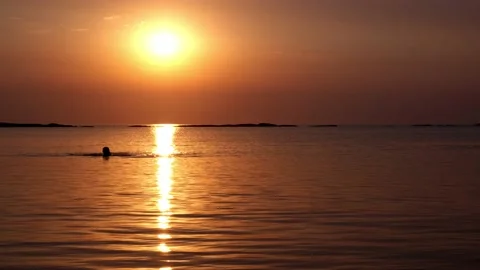 A man swims in the sunset rays of the sun on the sea. Peace and relaxation Stock-Footage 169414587