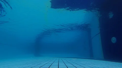 A man swims on the surface of the water in the pool from left to right. Shooting Stock Footage 120200271