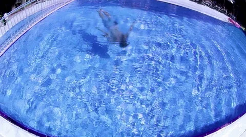 Man swims underwater in a swimming pool while on vacation in a resort Stock Footage