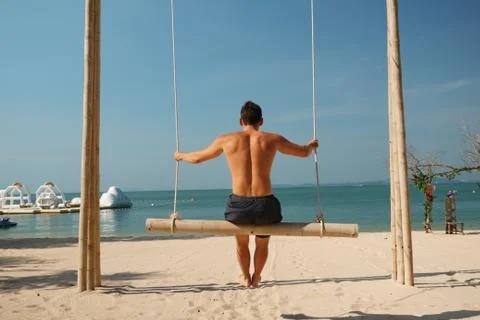 Man on a swing at the beach Stock Photos