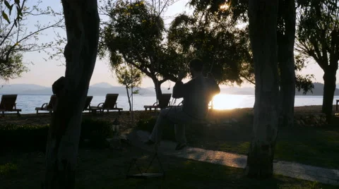 Man on swing, swinging at sunset Stock Footage 51365594