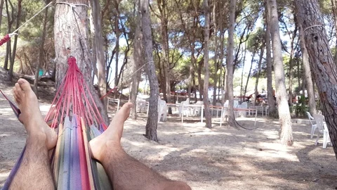 Man swinging on hammock in pine forest - legs and feet closeup Video stock 115524625