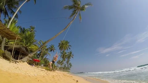Man swinging on a rope on the beach Video stock 86322965