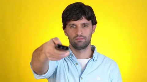 Man switches channels with remote control watches TV on a yellow background. Man Stock-Footage 145654282