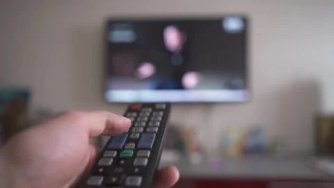 A man switches channels on a TV using the remote control Stock Footage 269955106