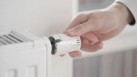 A man switches off the heating and opens the window ajar to let in fresh air. 库存影片 256646194