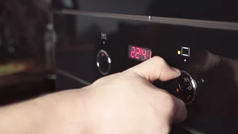 Man switches modes on the oven panel. The man's hand turns the knob to turn on Stock Footage 162710258