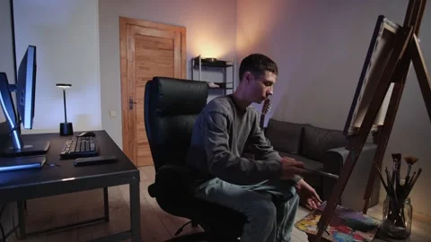 Man switching activities working on computer painting playing guitar Video stock 315430819