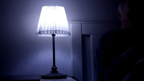 Man switching off a bedside table light before sleeping Stock Footage 128101584