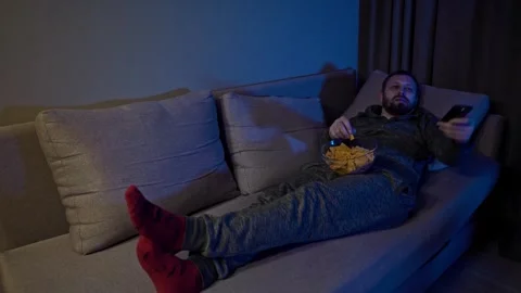Man switching channels while lying on the couch. Taking a nap. Stock Footage 313402942
