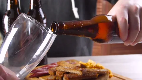 Man at the table with beer snacks pours beer into a glass Stock Footage 88582712