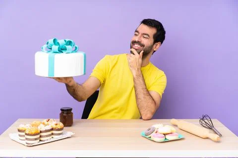 Man in a table with a big cake over purple backgroun Stock Photos
