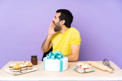 Man in a table with a big cake shouting with mouth wide open to the lateral Foto stock