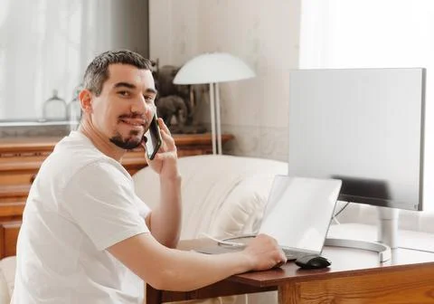 A man at a table with a computer talking on the phone Stockfoto's