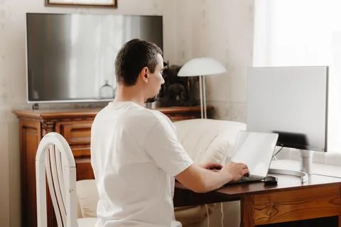 A man at a table with correct posture sits at a computer Stockfoto's