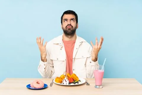 Man at a table having breakfast waffles and a milkshake frustrated by a bad s Foto stock
