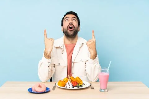 Man at a table having breakfast waffles and a milkshake surprised and pointin Stock Photos